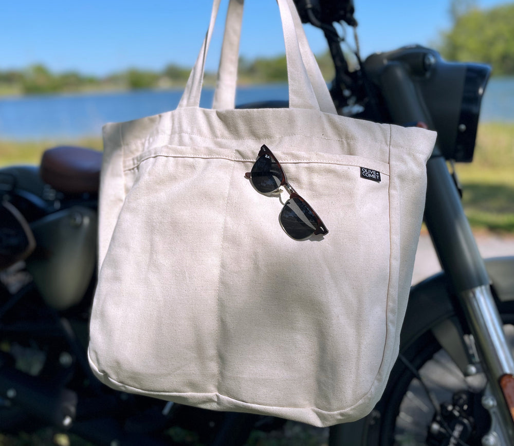 Ckloseup photo of an Olive+Comet Sonoma bag hanging on the handlebars of a vintage motorcycle