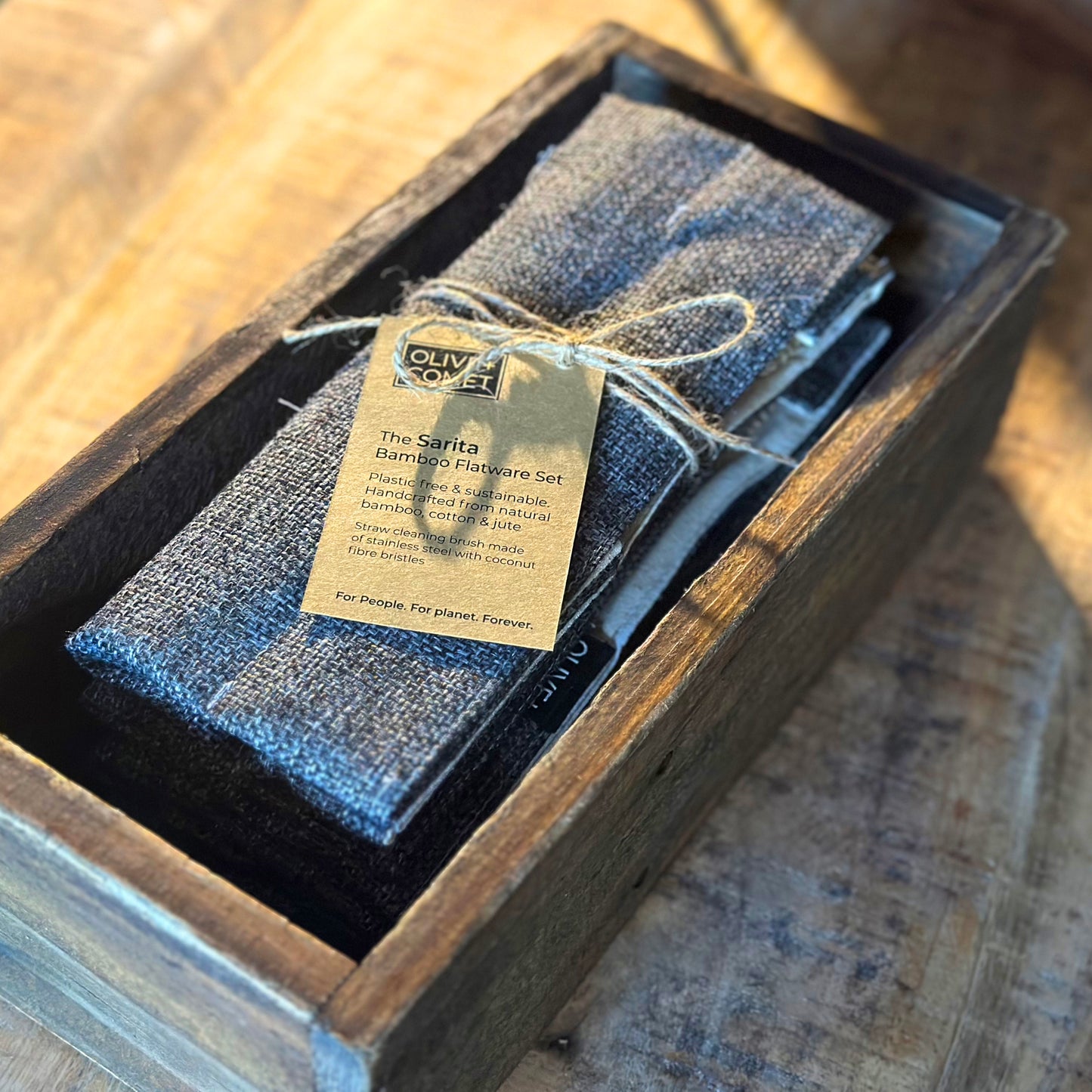 A Sarita bamboo flatware set is tied closed with jute twine and rests in an old farmhouse style box