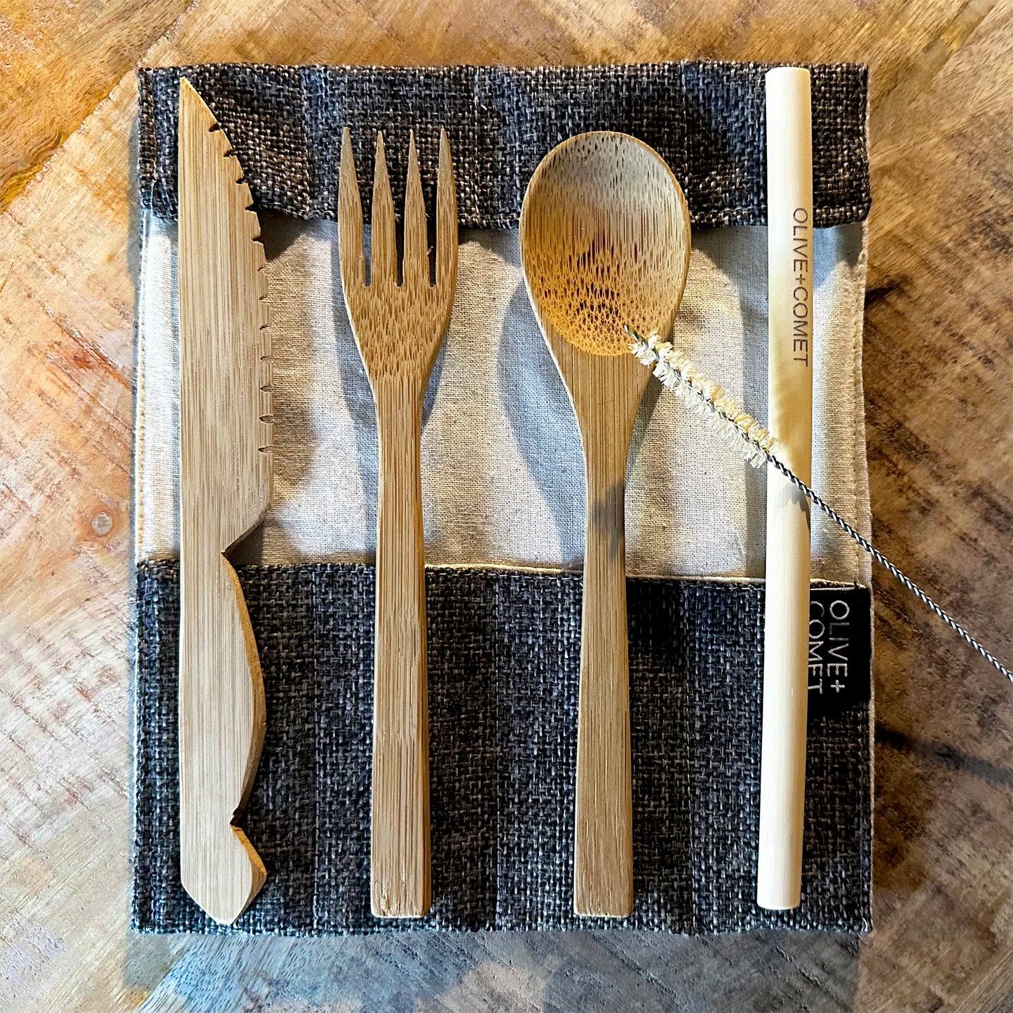 A Sarita bamboo flatware set lies open on a mango wood table
