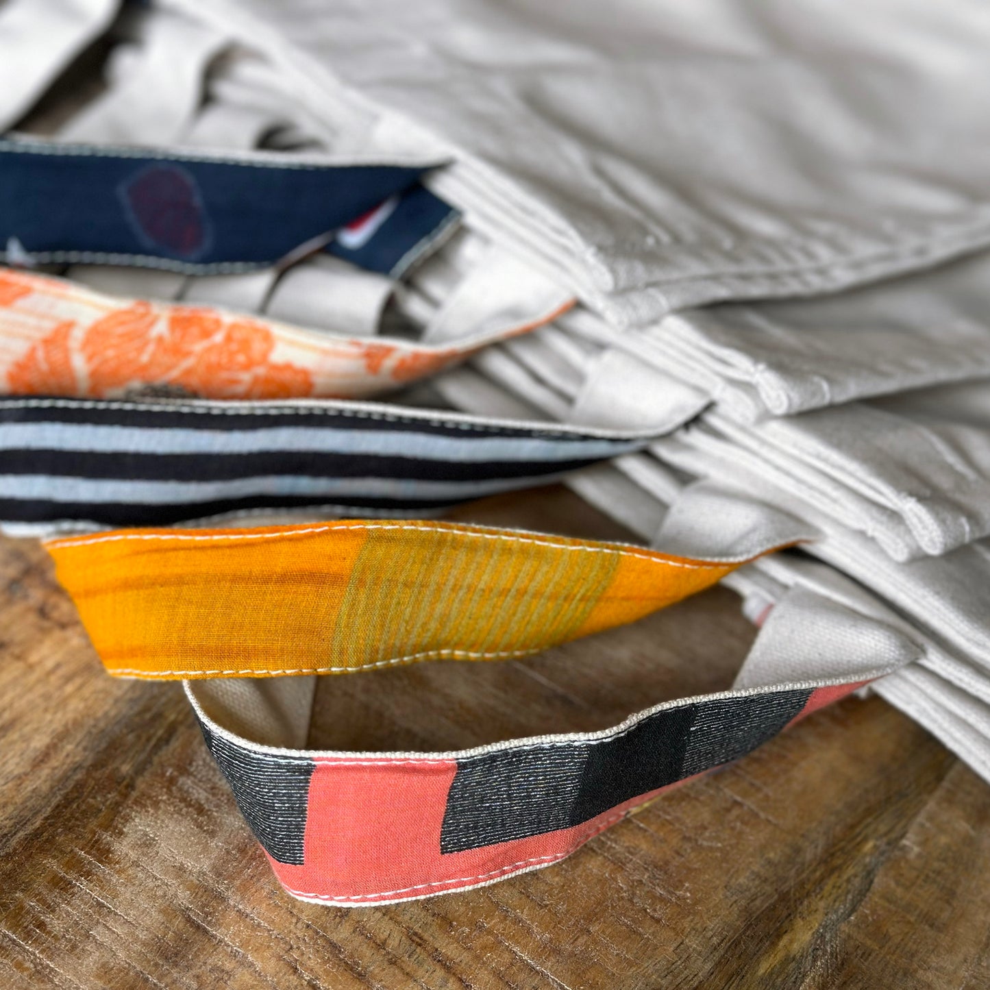 Several Parker bag handles shown side by side, ranging from brilliant golden yellow to navy blue with red accents.