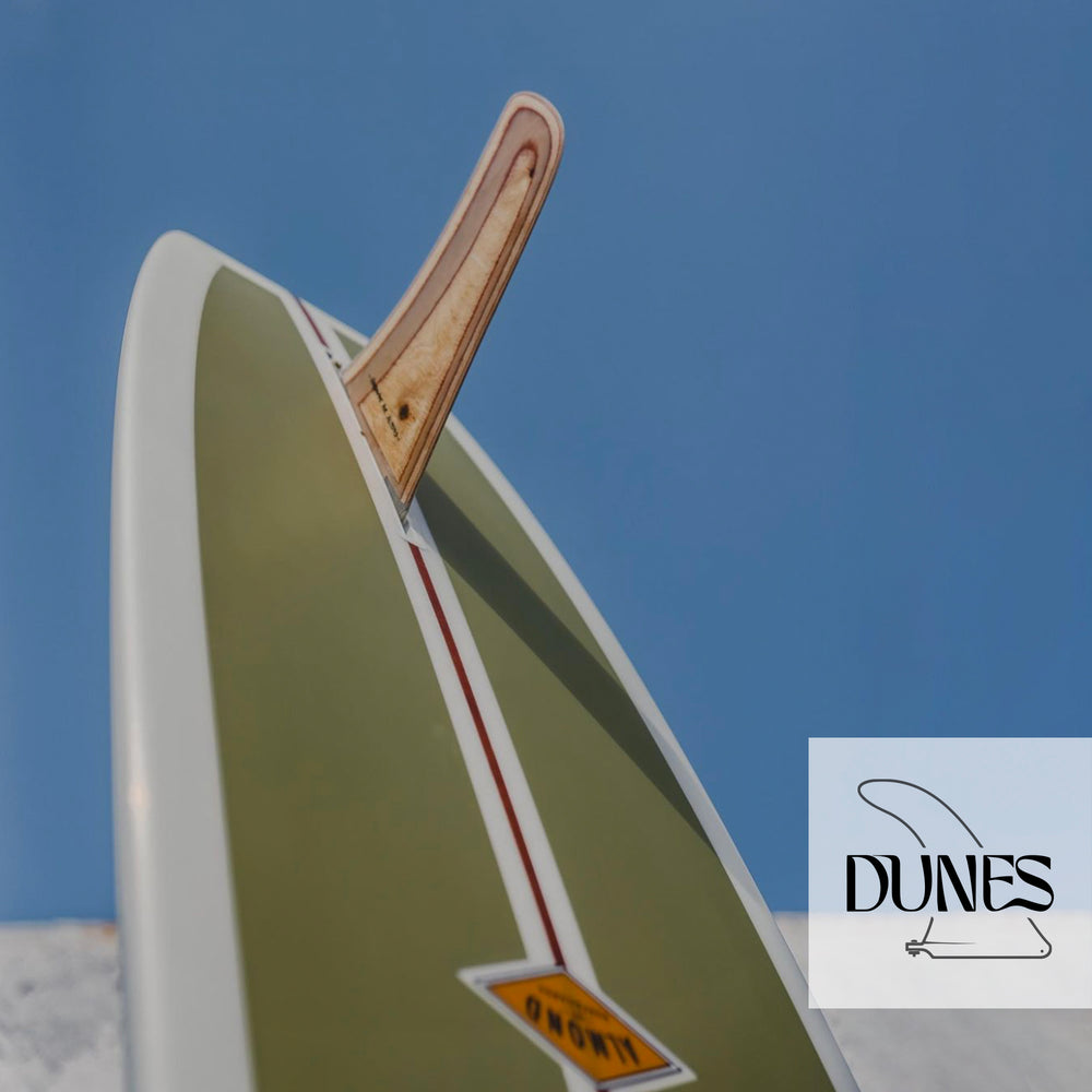 An Almond brand surboard and fin shot against a blue sky