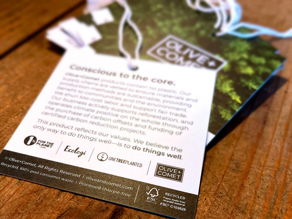 A photo of Olive+Comet product tags bearing FSC® certification and showing PCW content
