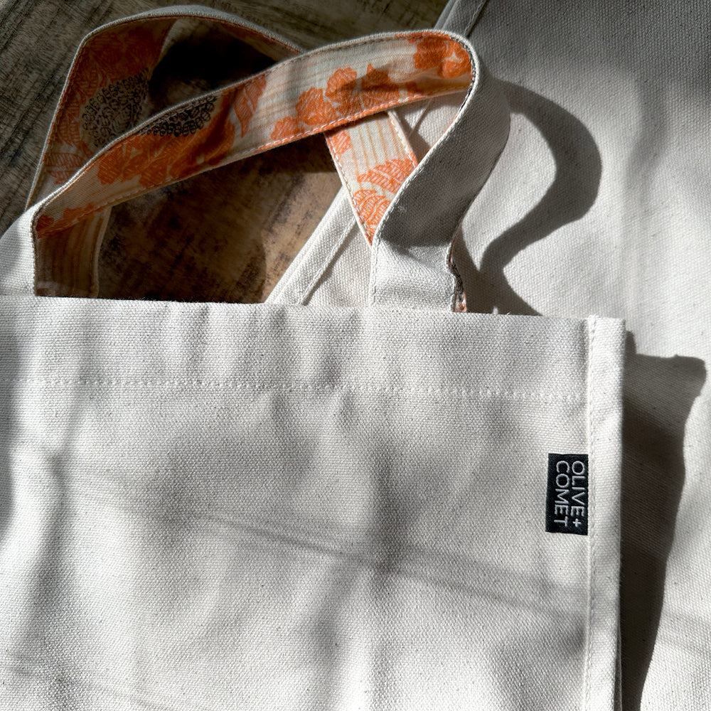 
                  
                    closeup of a Parker bag shows off the dusty orange color of an upcycled sari lining on it's handles
                  
                