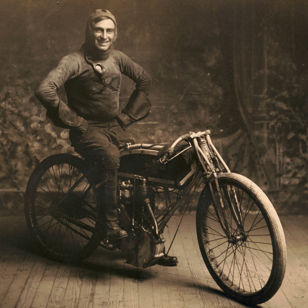 Famed early motorcycle racer Ray Weishaar poses on his bike in a waxed canvas racing suit