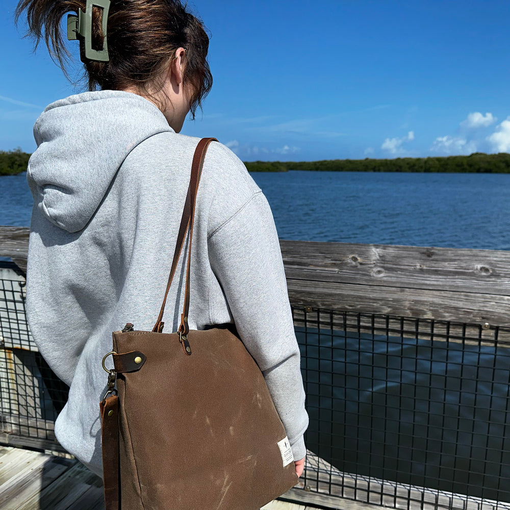 
                  
                    A woman in a hoodie looks out at a lake with a Marquesa bag on her shoulder
                  
                