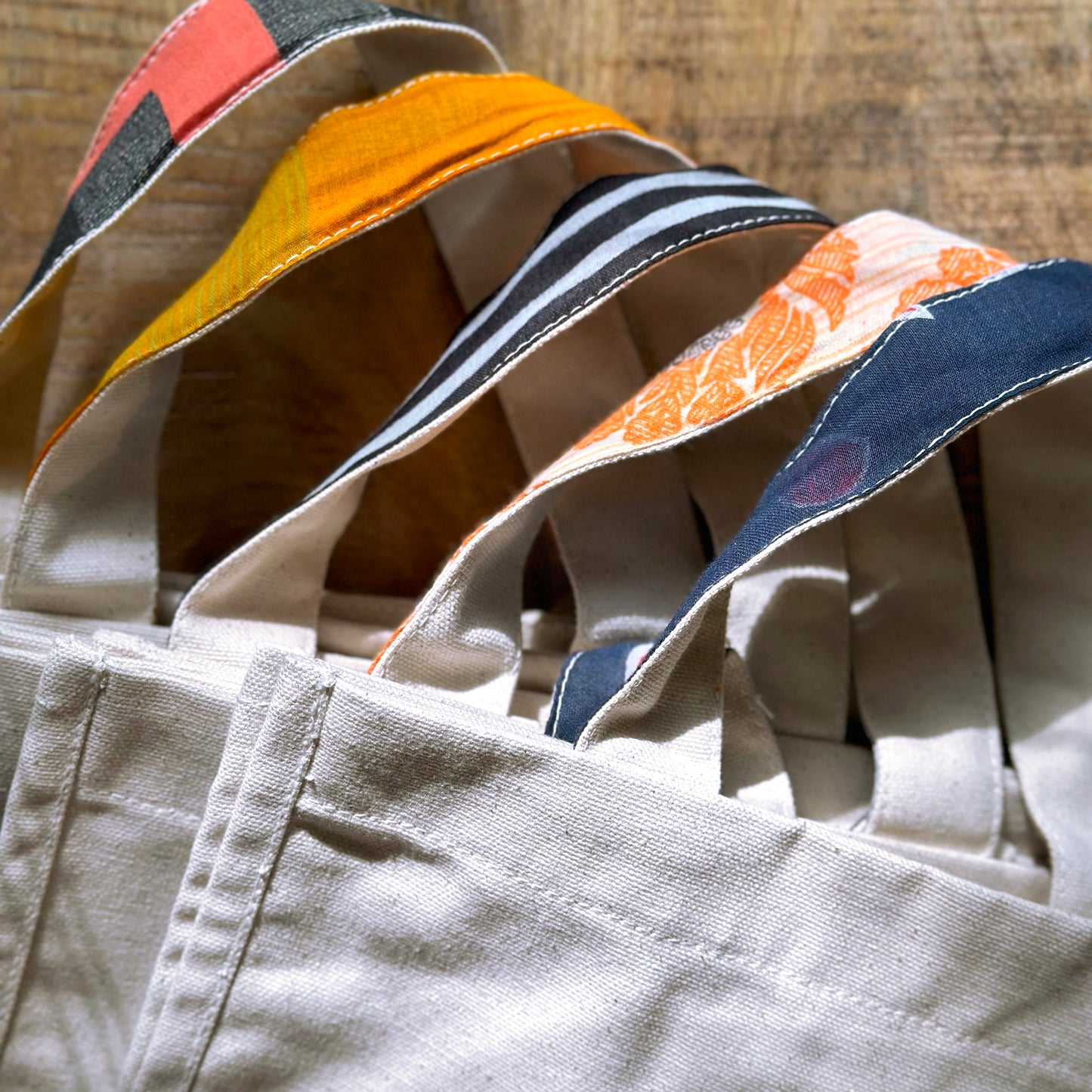 Several Parker bags lie in a row showing a range of colors from the upcycled sari handle linings.